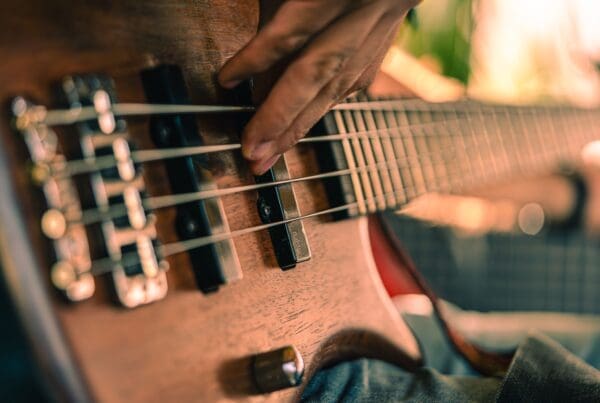 A detailed shot of a musician playing a bass guitar, showcasing musical performance intensity.